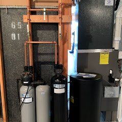 A room with a lot of pipes and a water heater.