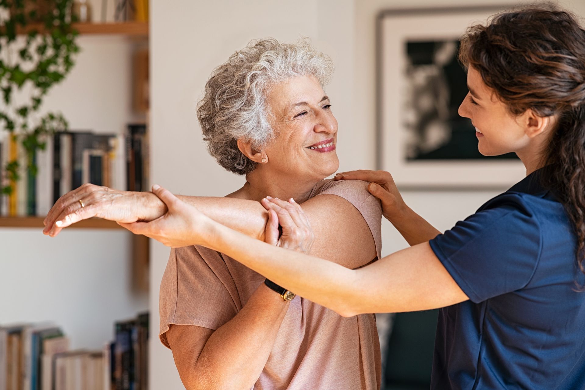 Woman stretches arm with help from caregiver.