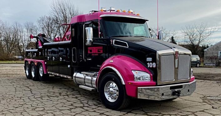 Black and pink Kenworth tow truck. Bright pink accents on the fenders, roof, and door trim.