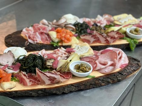 Due vassoi di legno con carni assortite, formaggi, olive e guarnizioni, pronti per essere serviti.
