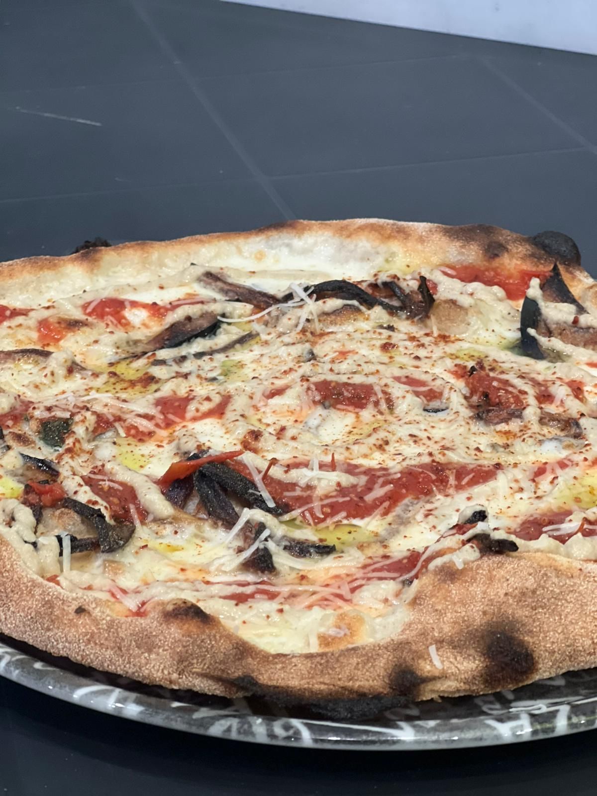 Pizza con funghi, salsa di pomodoro e formaggio su un piatto.