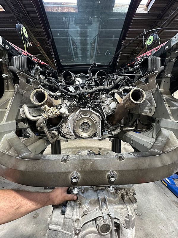 A man is working on a car with the hood up in a garage.