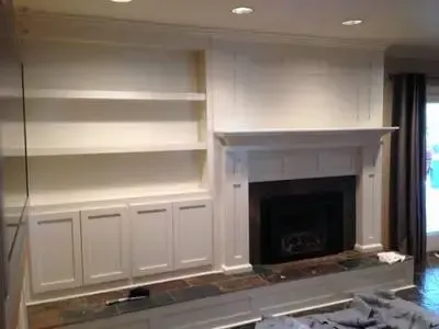 A living room with a fireplace , shelves and cabinets.