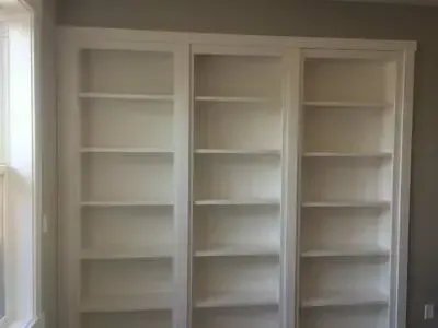 A room with a lot of shelves and a window.