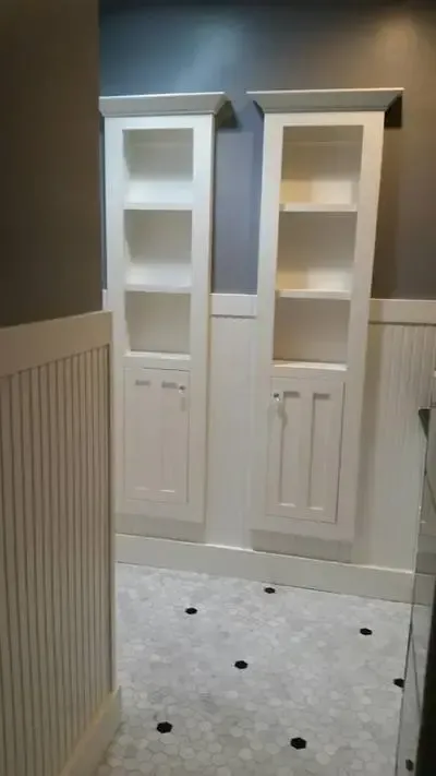 A bathroom with two white cabinets and a tile floor.