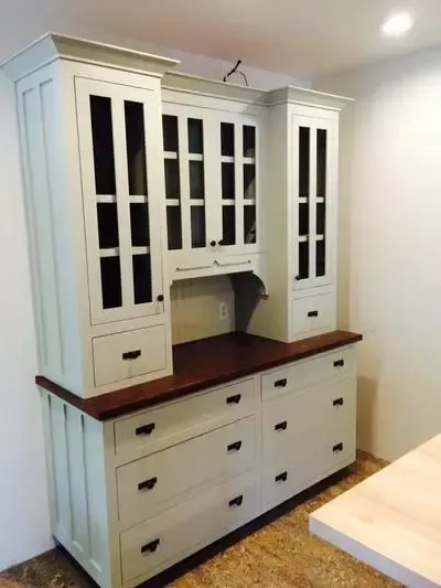 A white cabinet with lots of drawers and glass doors
