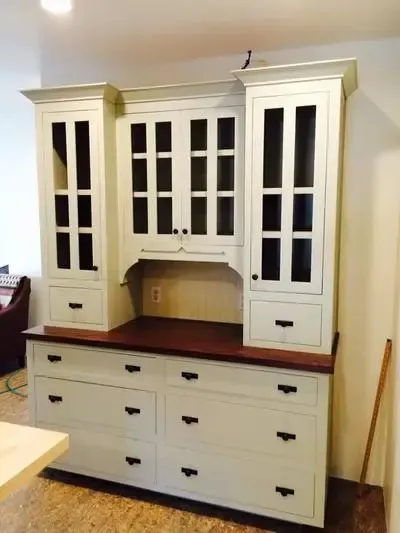 A white cabinet with drawers and glass doors in a kitchen