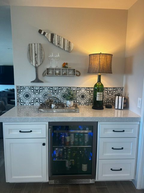 A kitchen with white cabinets and a wine fridge