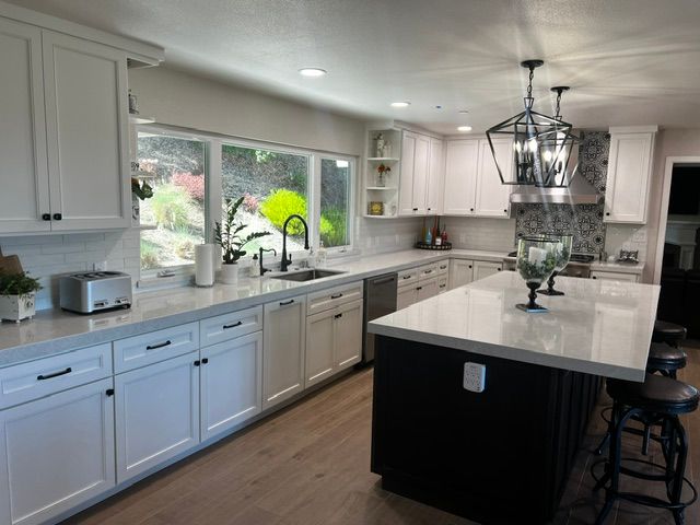 A kitchen with white cabinets and a black island.