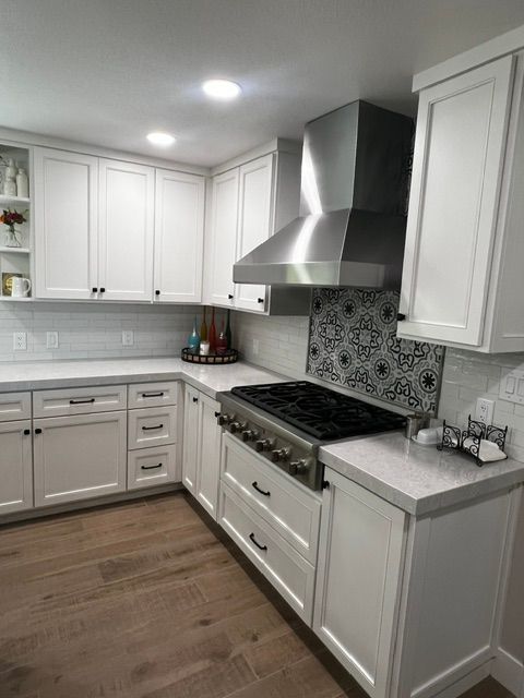 A kitchen with white cabinets and a stove top oven