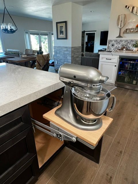 A kitchen aid mixer is sitting on a wooden shelf in a kitchen