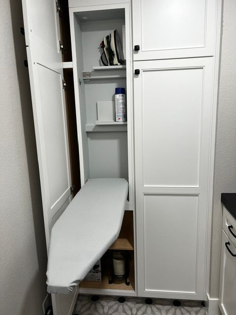 A white cabinet with an ironing board inside of it