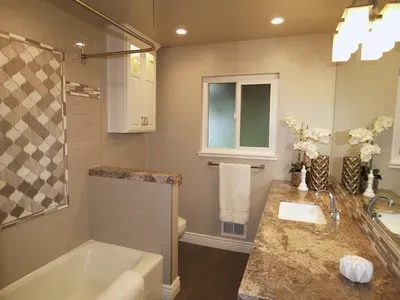 A bathroom with a tub , sink , mirror and window.