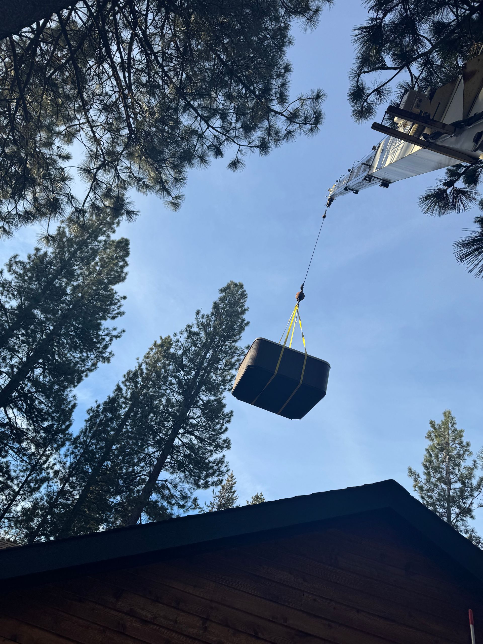 A large box is being lifted by a crane over a house