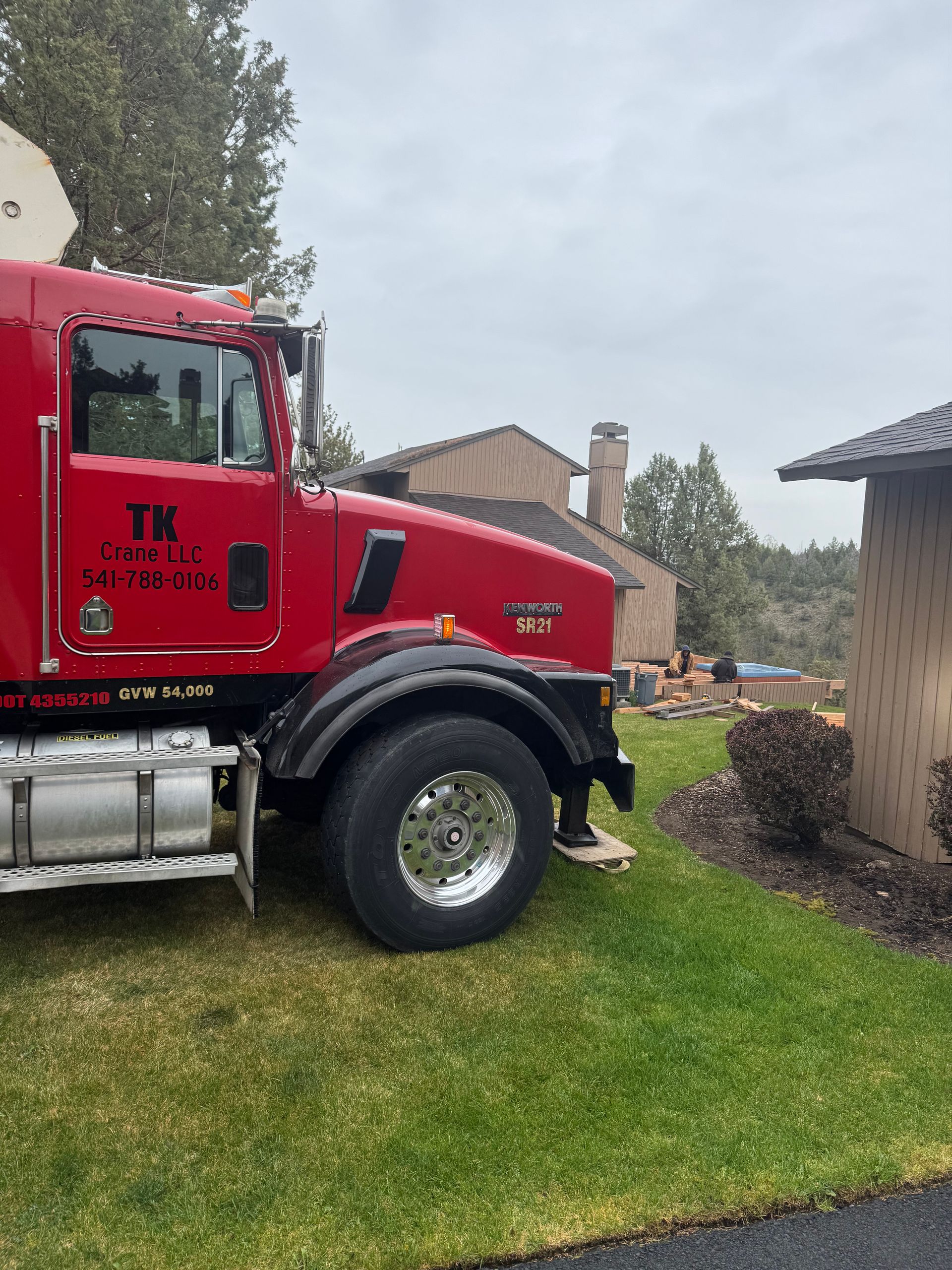 A red semi truck is parked in front of a house.