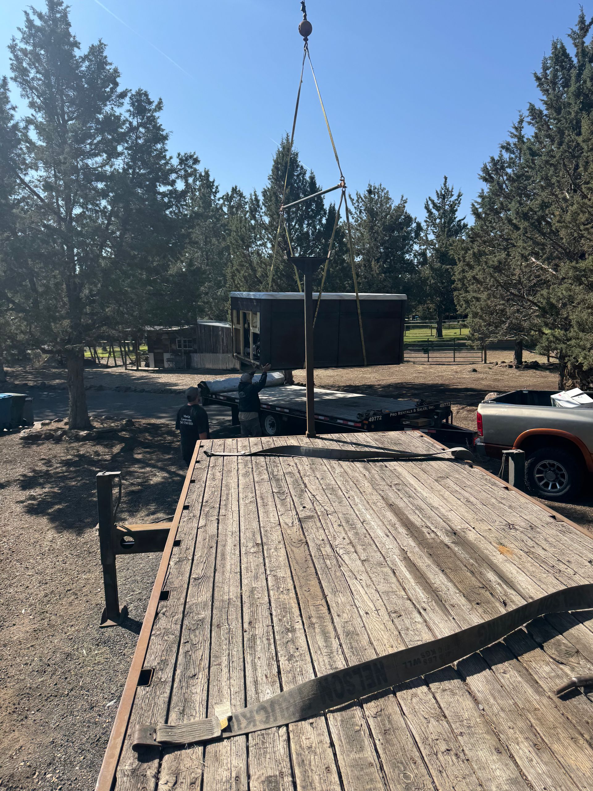 A wooden trailer is being lifted by a crane