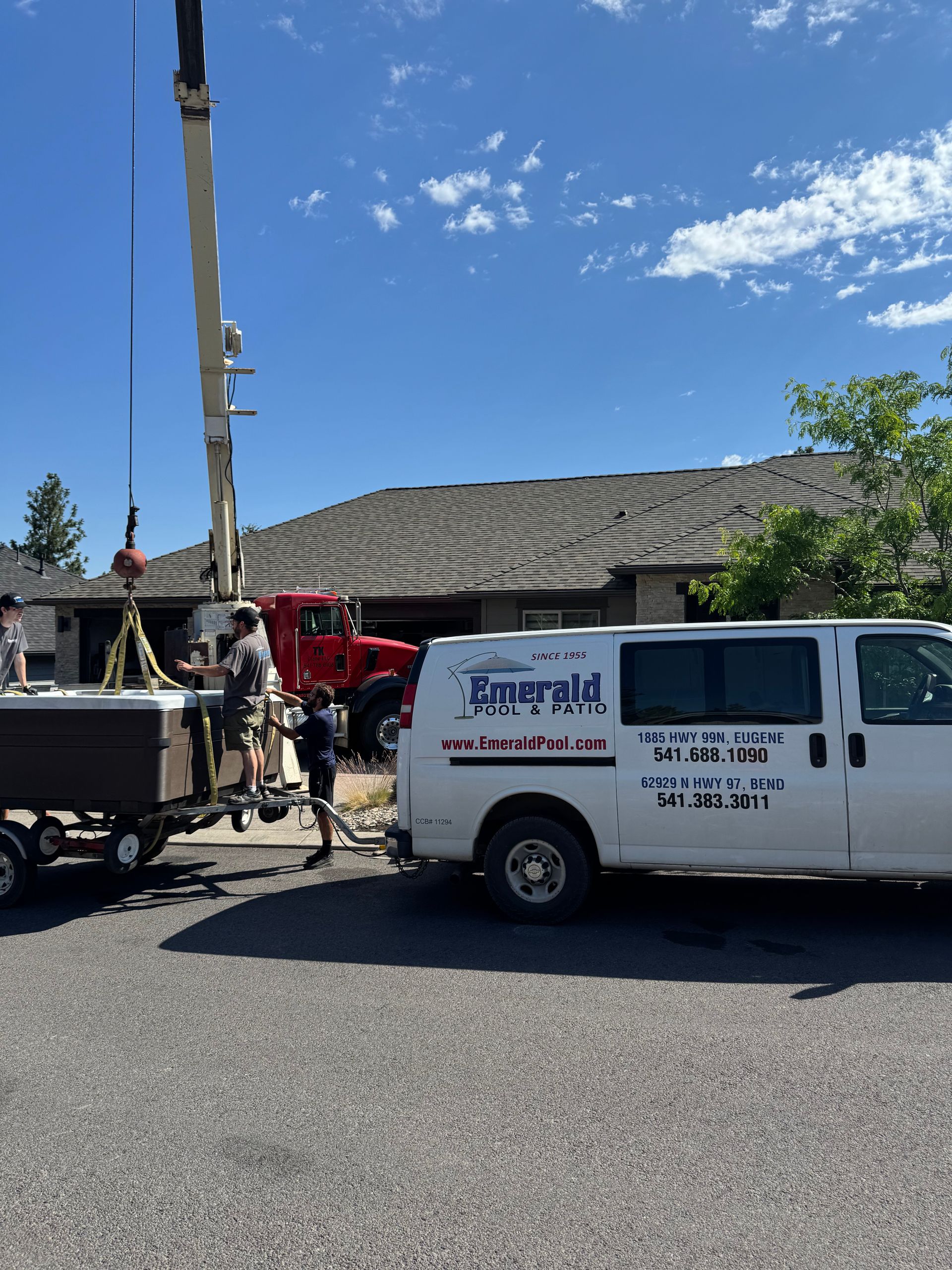 A white van is parked in front of a house with a crane attached to it.