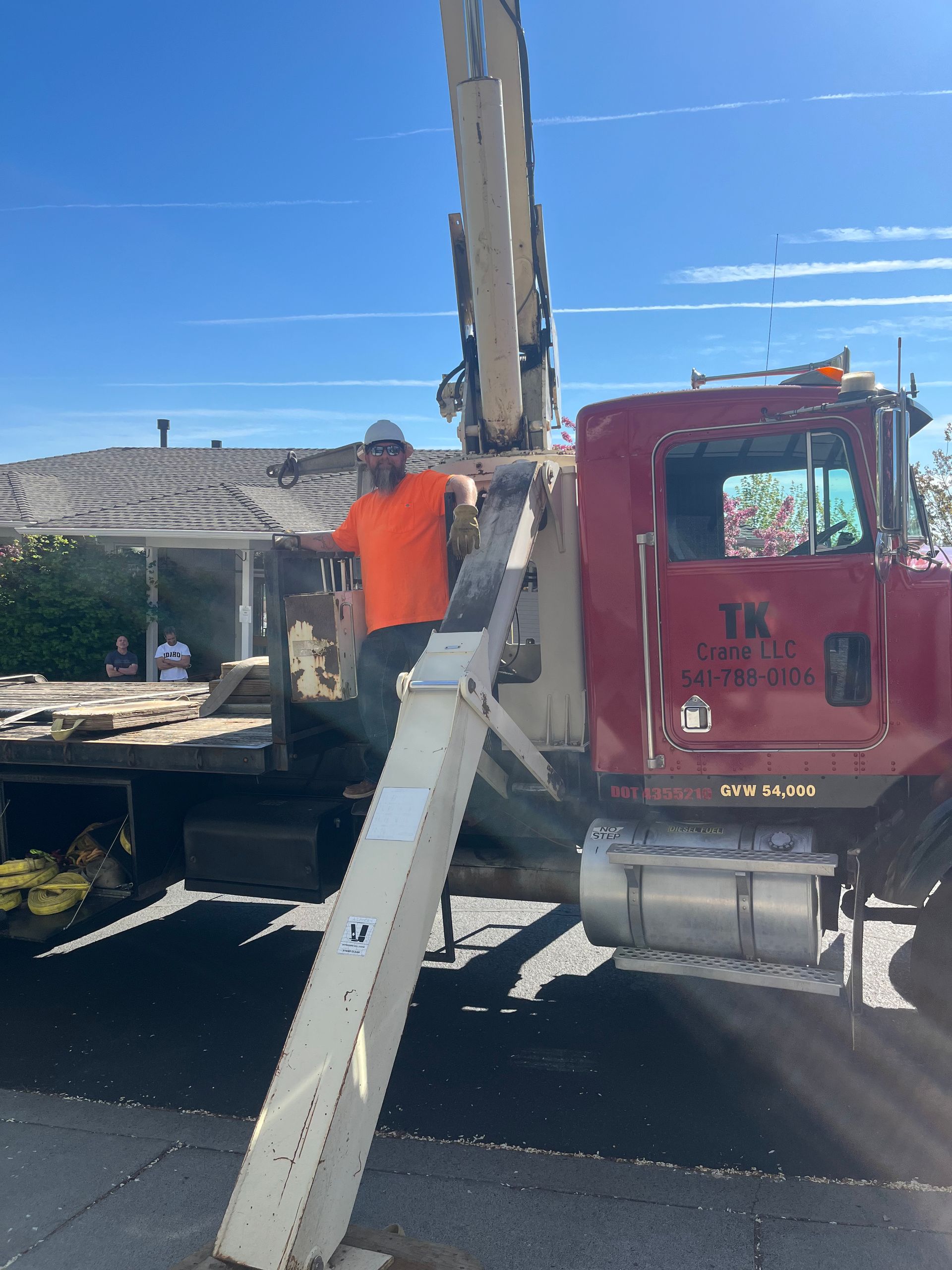 A man is standing on the back of a red truck.