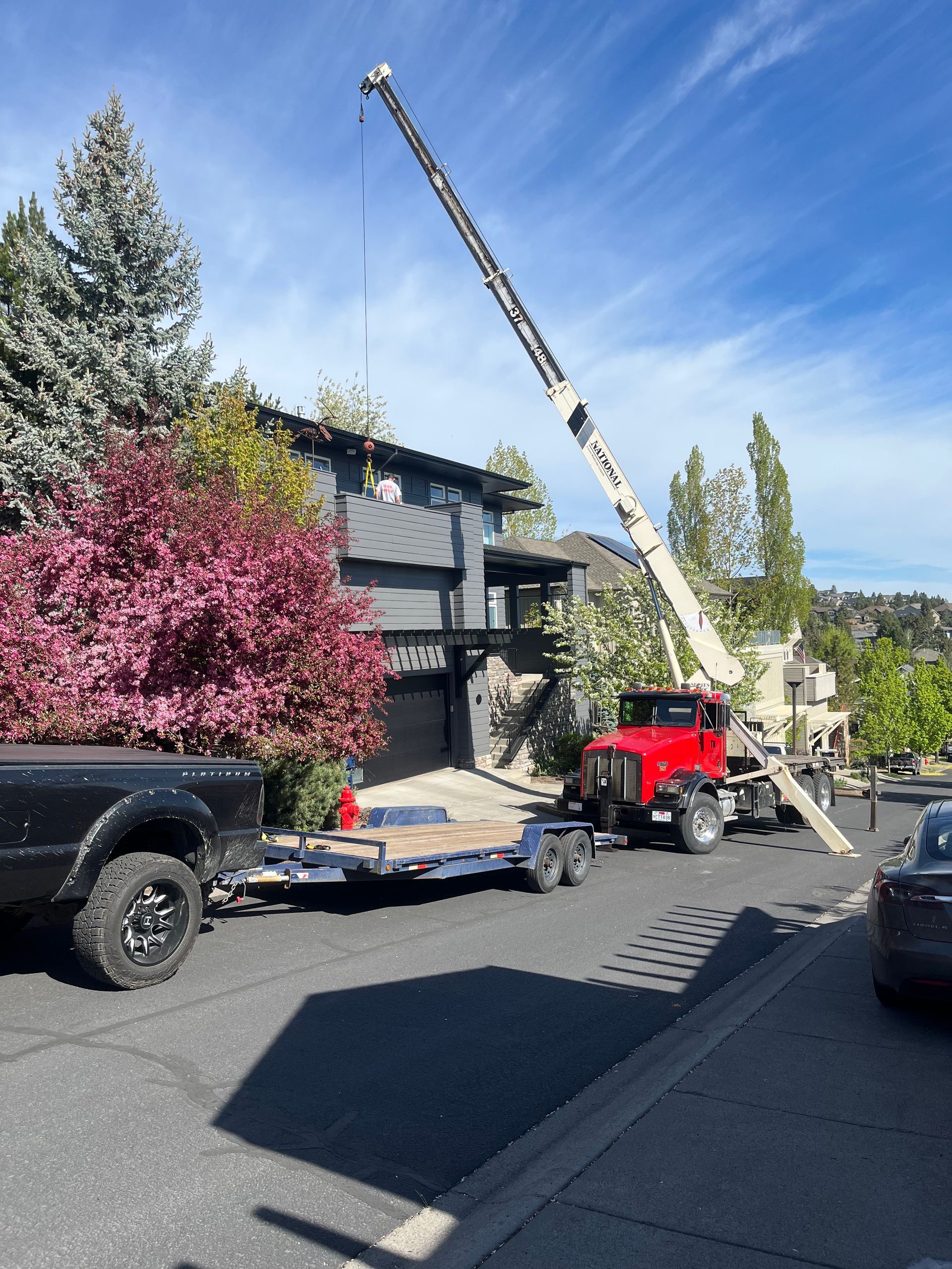 A truck is towing a trailer with a crane attached to it.