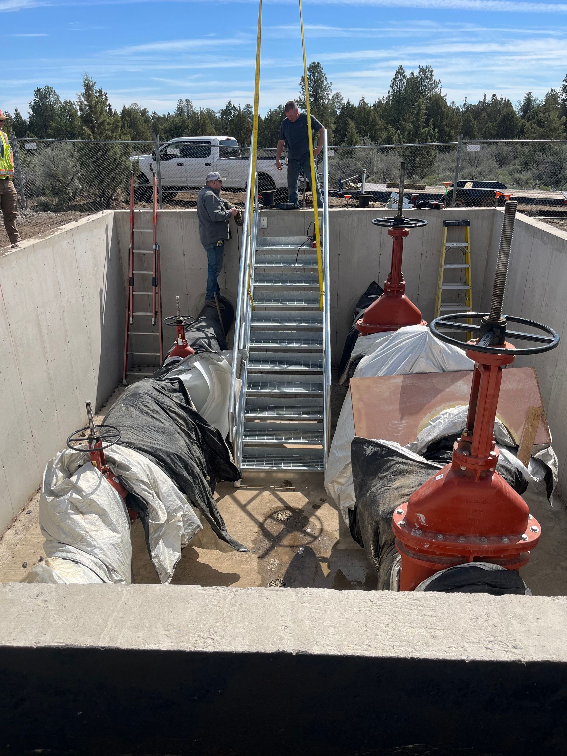 A man is standing on top of a staircase surrounded by pipes and valves.