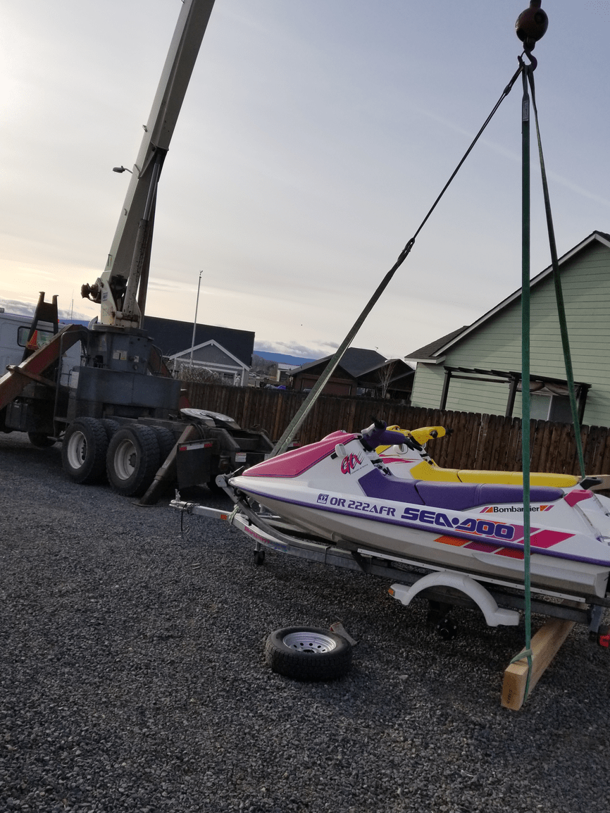 A jet ski on a trailer is being lifted by a crane
