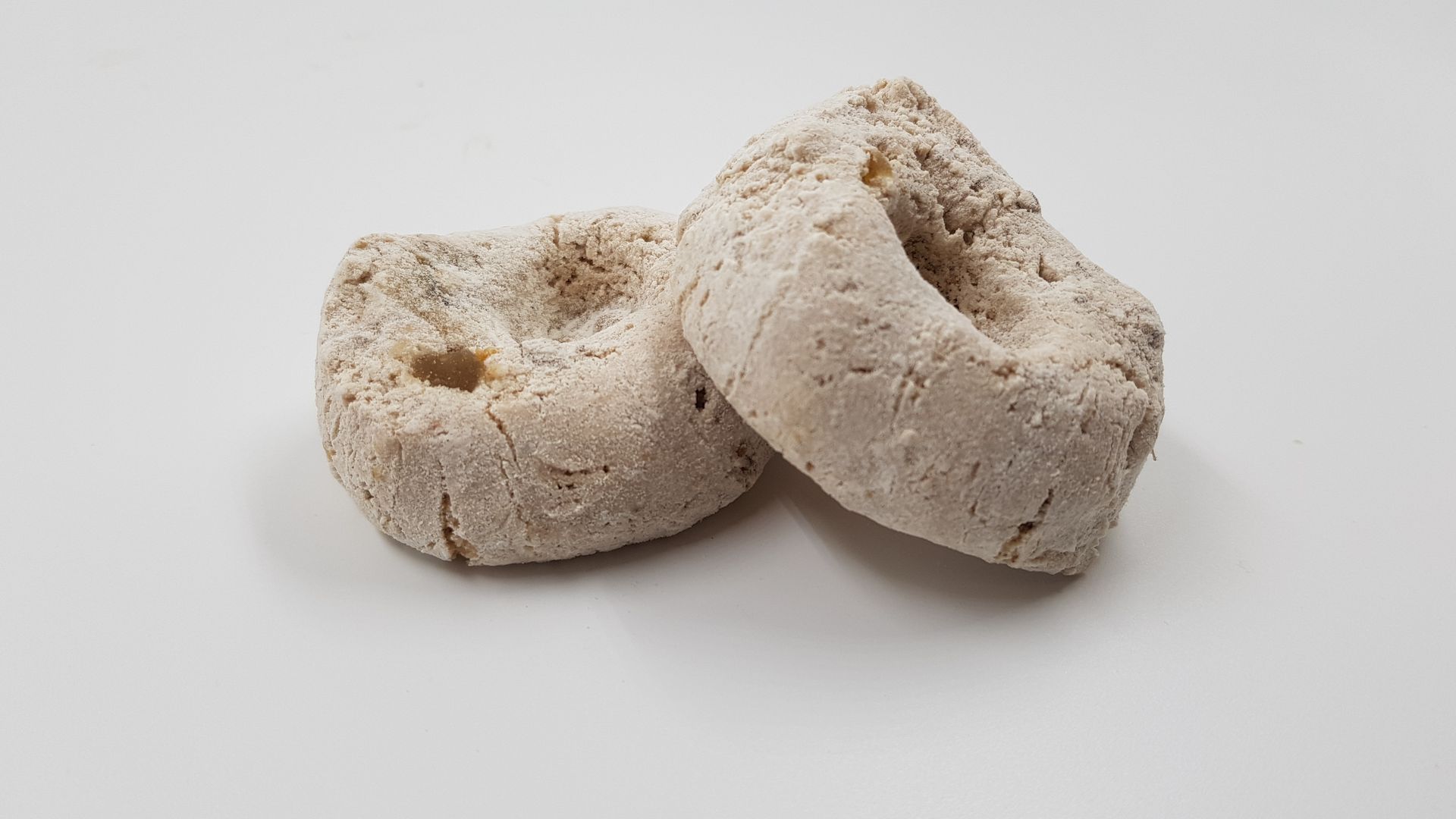 Due ciambelle sono appoggiate una sopra l'altra su una superficie bianca.