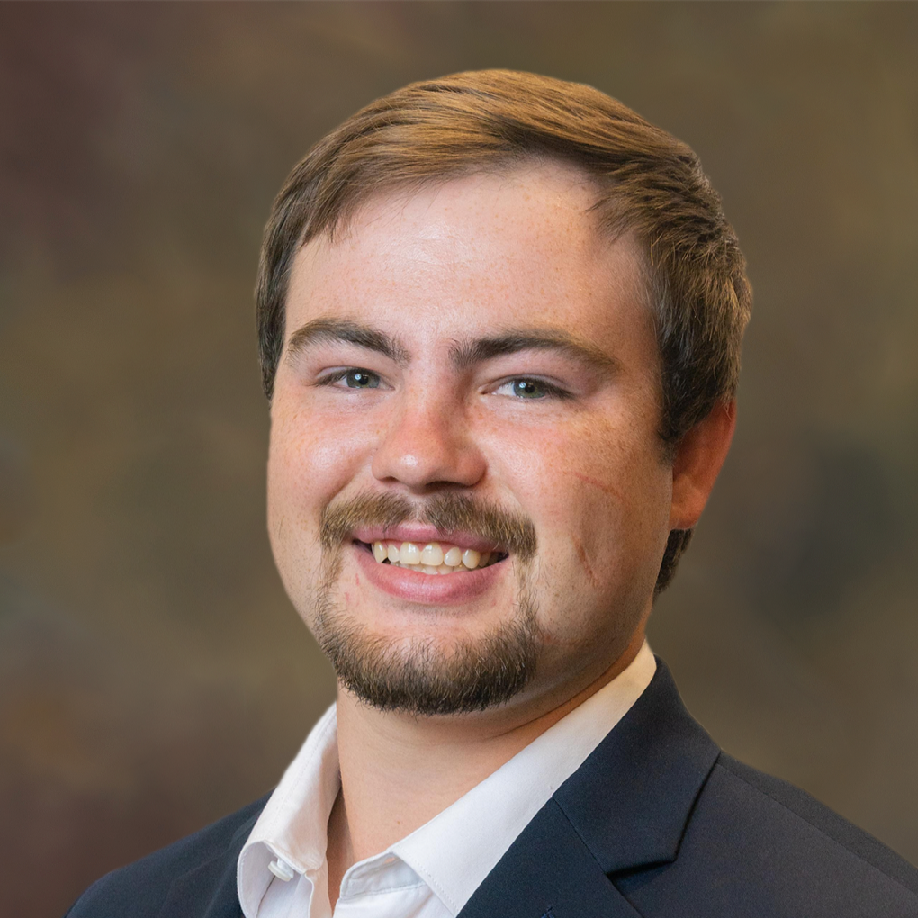 A man in a suit and white shirt is smiling for the camera.