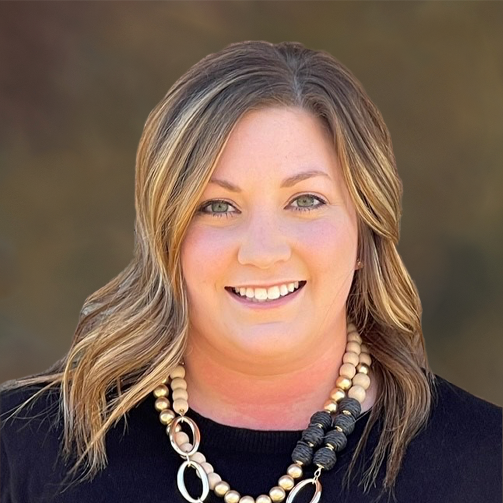 A woman wearing a black shirt and a necklace is smiling for the camera.