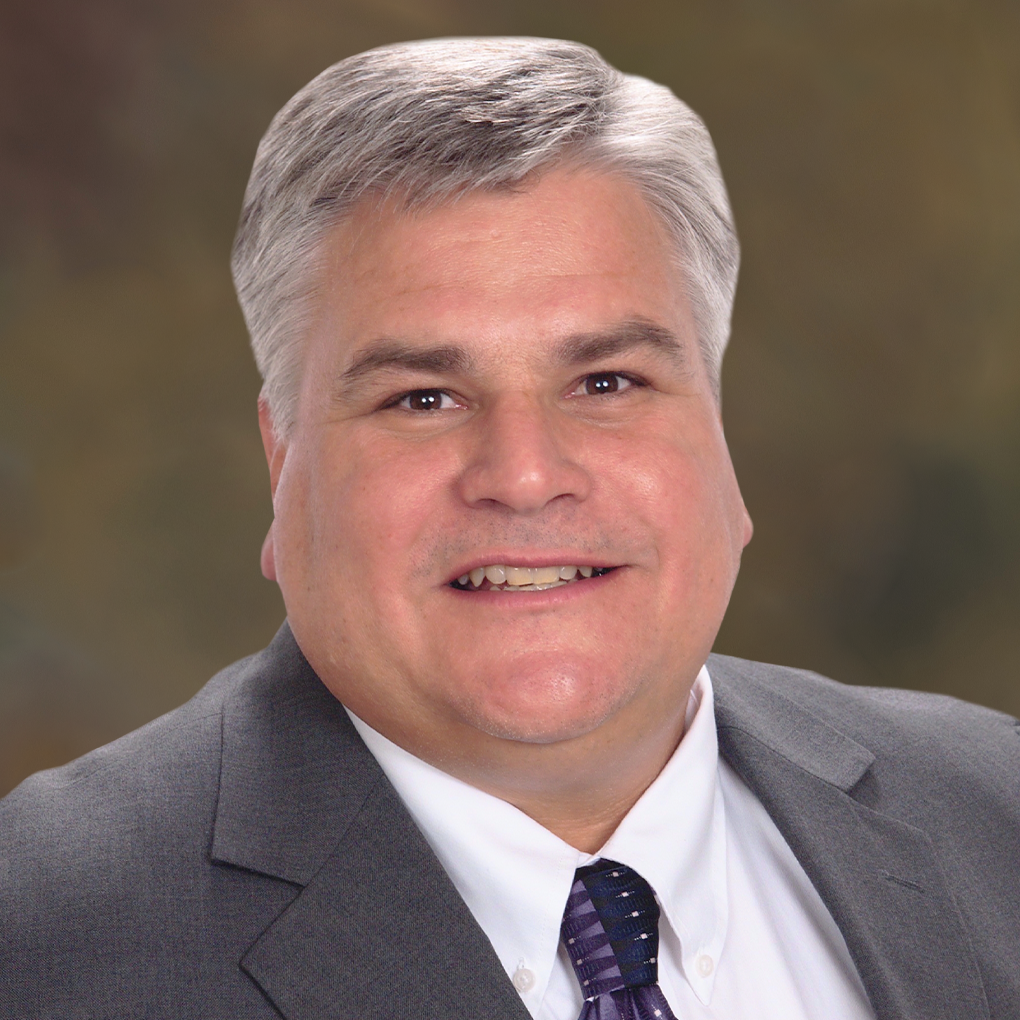 A man in a suit and tie is smiling for the camera