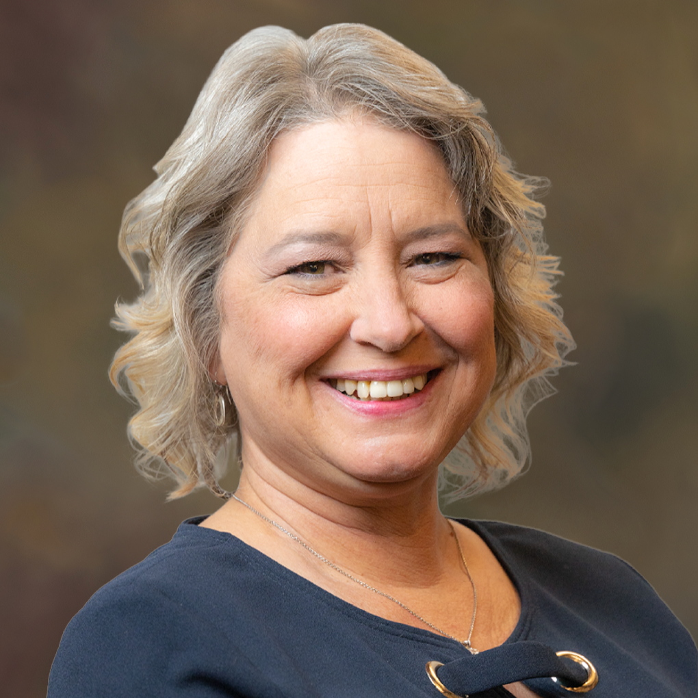 A woman in a blue shirt is smiling for the camera.