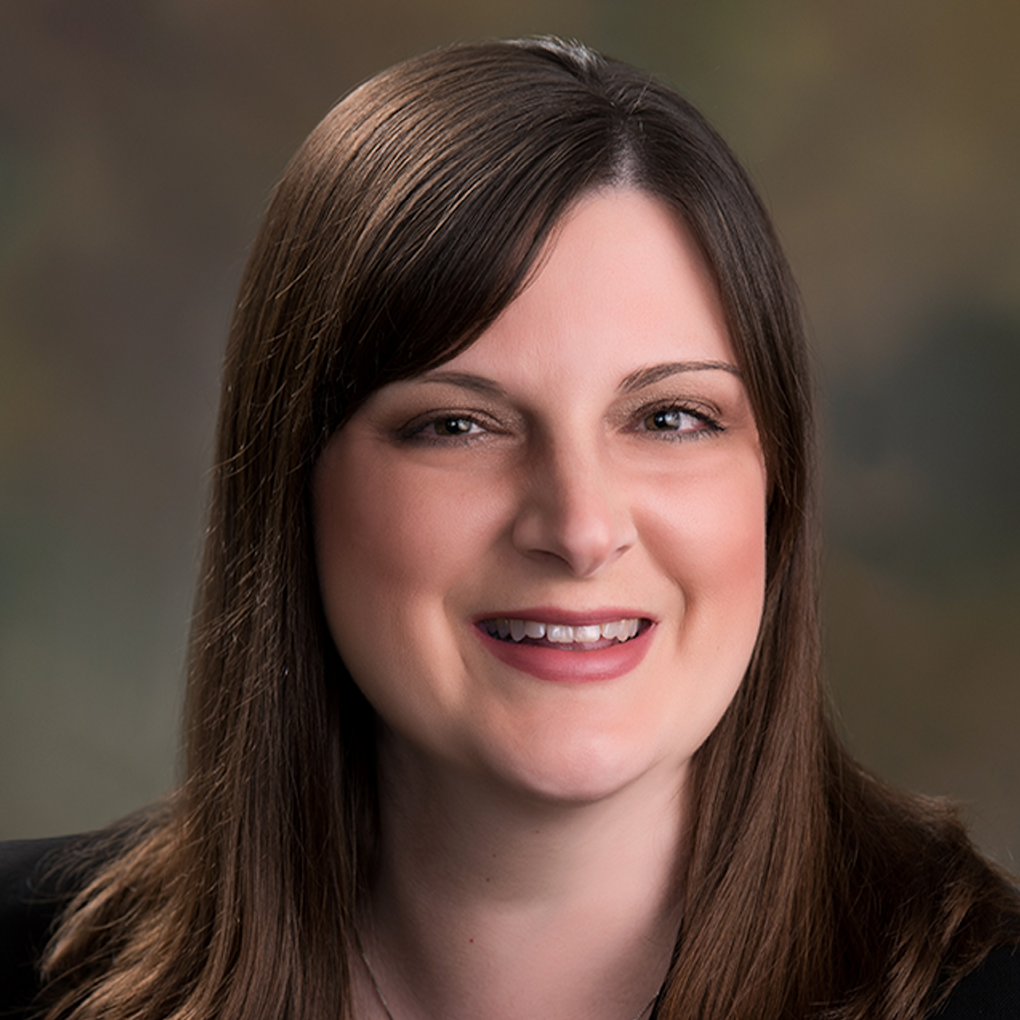 A woman with long brown hair is smiling for the camera.