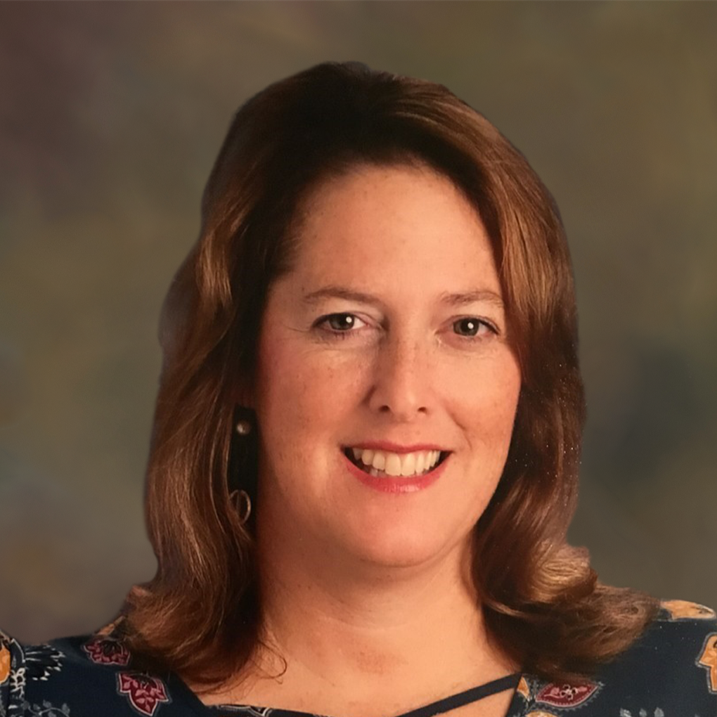 A woman in a blue shirt is smiling for the camera.