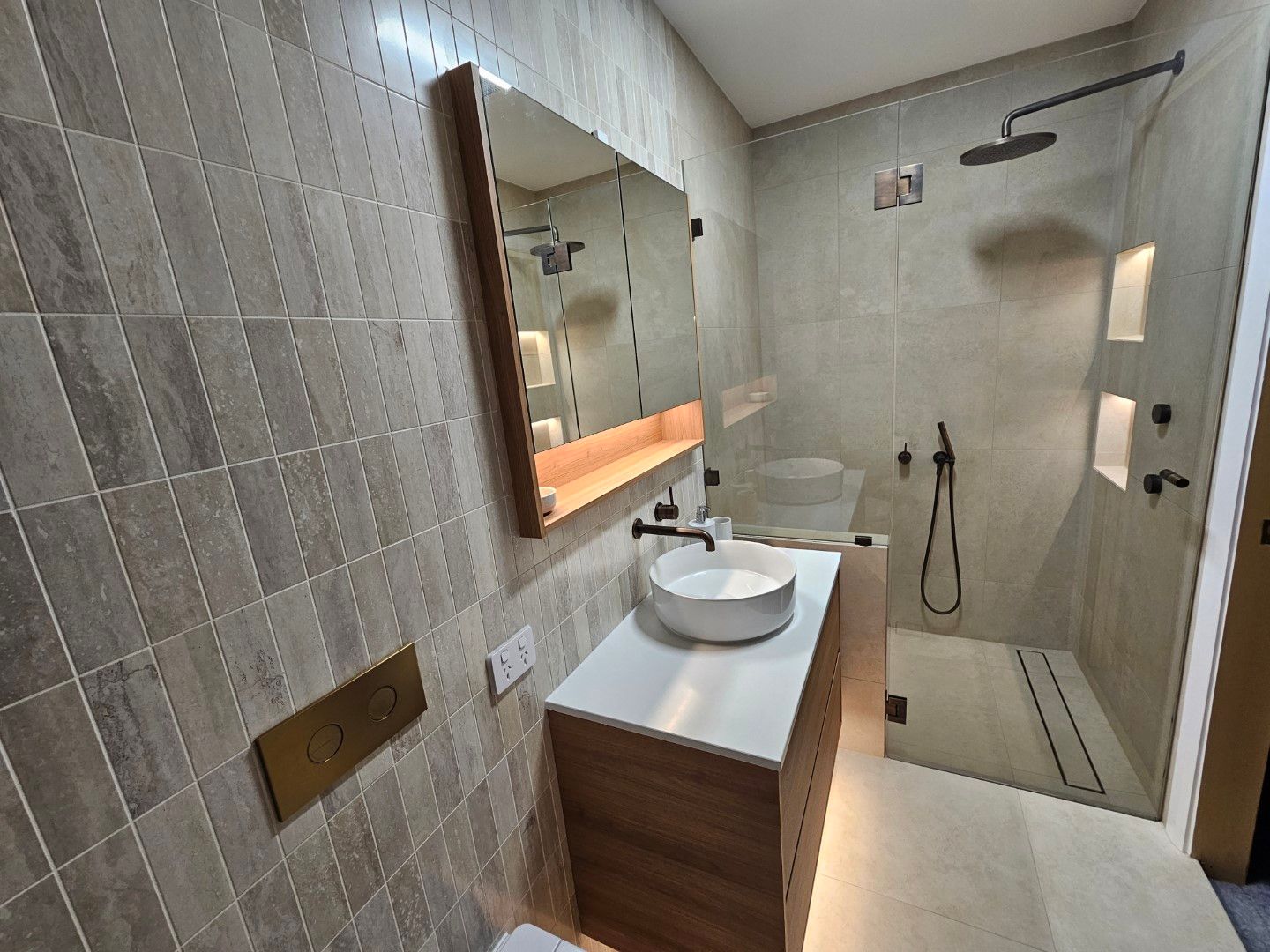 Bathroom with gray tile walls, a wood vanity, and a walk-in shower — North Coast Tiles in Grafton, NSW