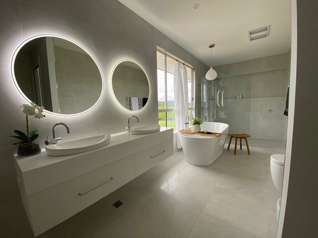 Modern bathroom with white floating vanity and round mirrors — North Coast Tiles in Grafton, NSW