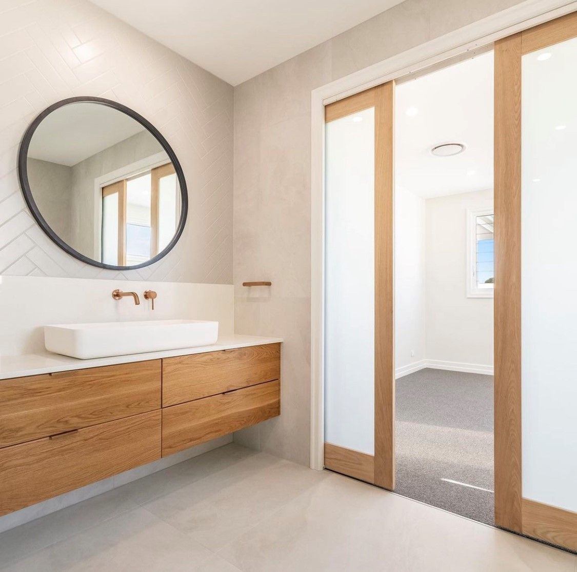Bathroom with wood vanity, a round mirror and a sliding door — North Coast Tiles in Grafton, NSW