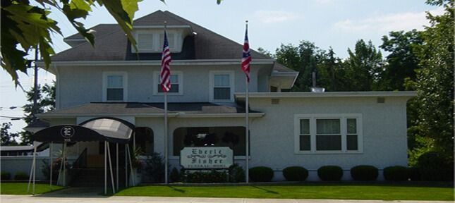 Exterior of a two-story building with American and British flags. 