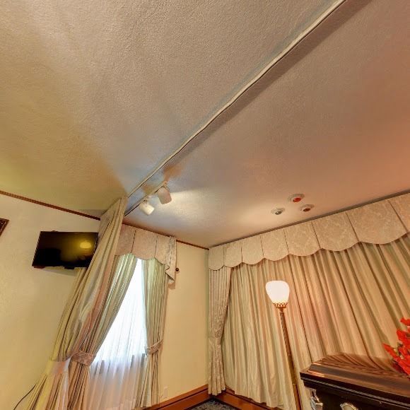 Interior room with curtains, a lamp, and a TV.