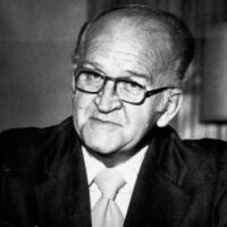 Man wearing glasses and suit, looking at camera.