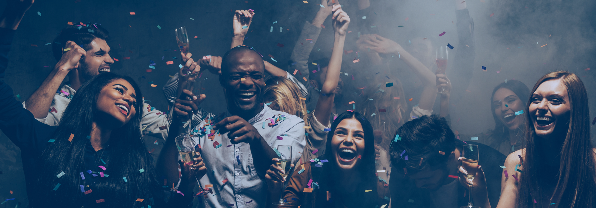 Group of people smiling and cheering in a confetti-filled party scene with raised hands
