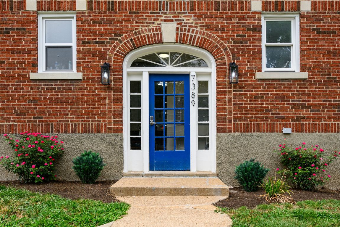 A brick building with a blue door and a walkway leading to it.