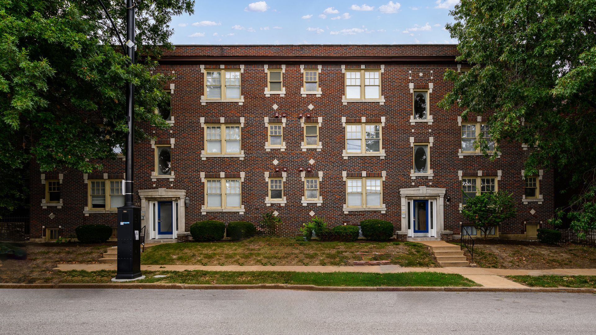 A large brick building with a lot of windows and trees in front of it.