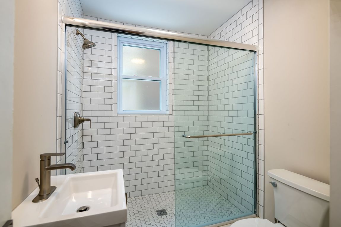 A bathroom with a sink , toilet and shower with sliding glass doors.