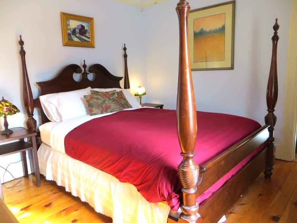 A bedroom with a four poster bed and a lamp