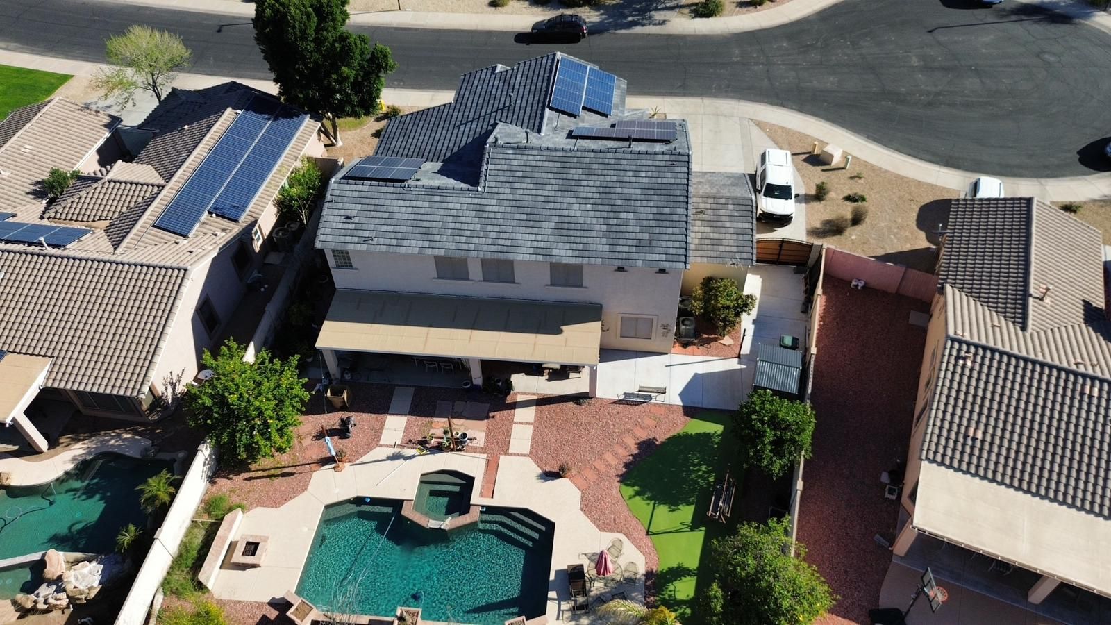 Aerial view of a two-story house with a pool and solar panels on the roof.