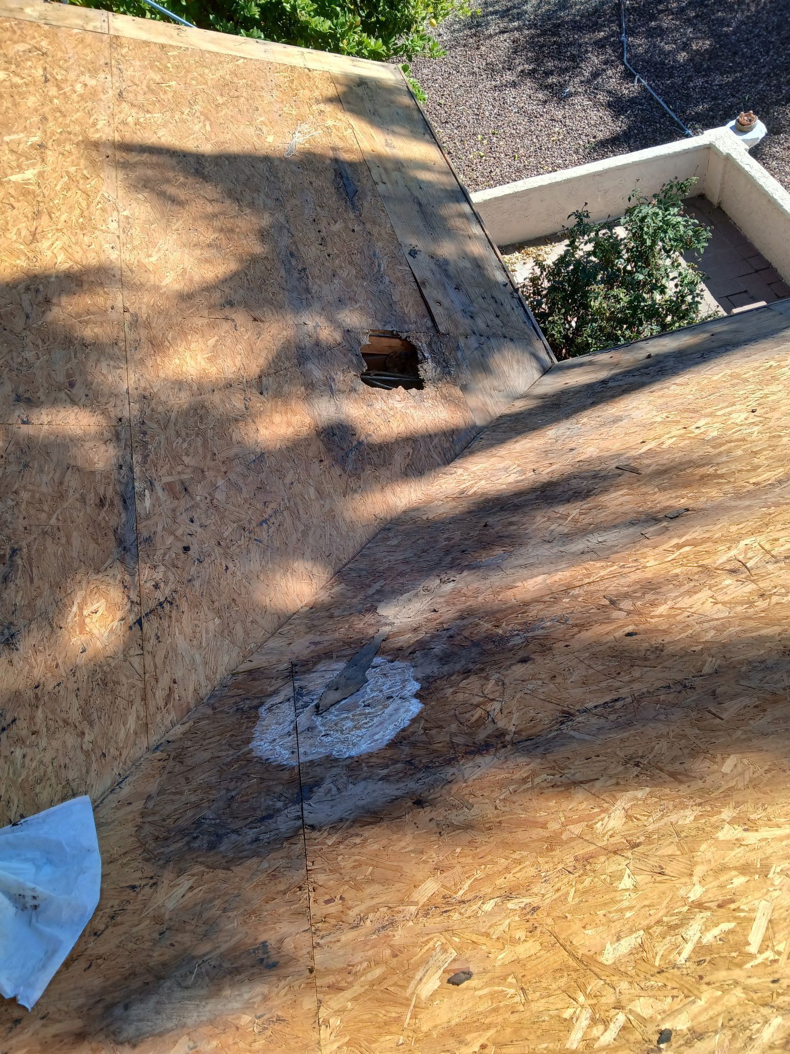 View of damaged wooden roof with hole and discoloration, possibly from water damage.