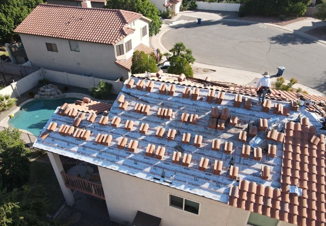 Asphalt shingle roof with a skylight, trees in the background.
