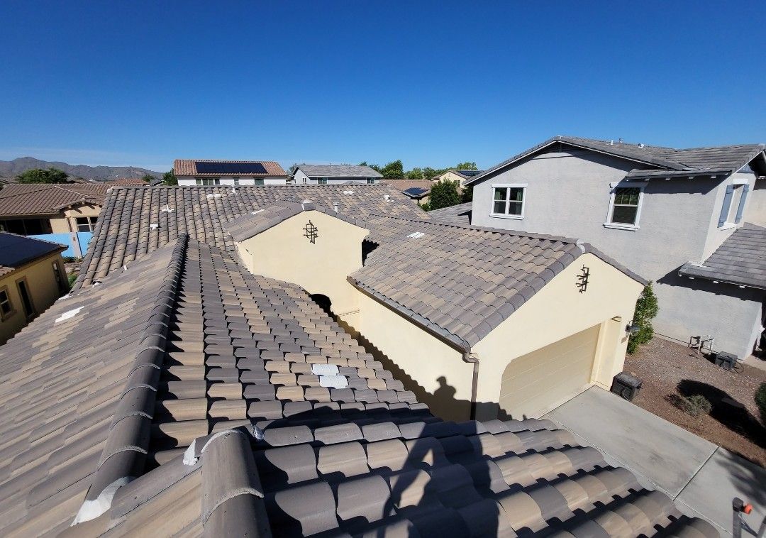 View of rooftops in a sunny suburban neighborhood. Tile roofs and clear blue sky.