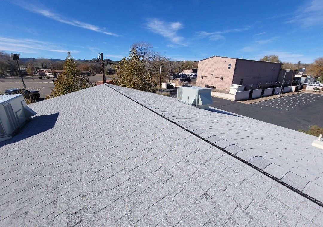 Gray shingle roof, clear blue sky, buildings in background, sunny day.