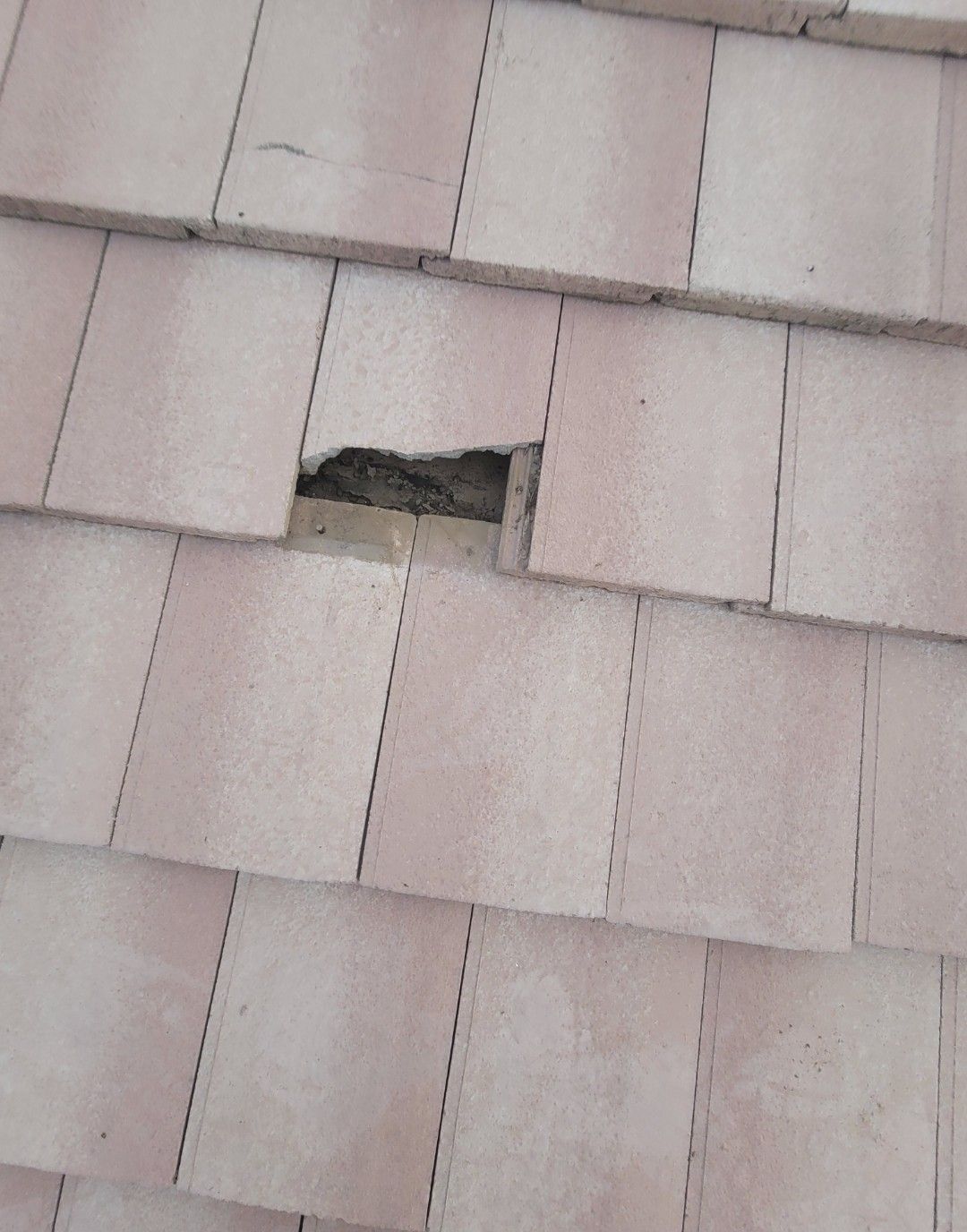 Close-up of a roof with a damaged tile, revealing the underlayment.