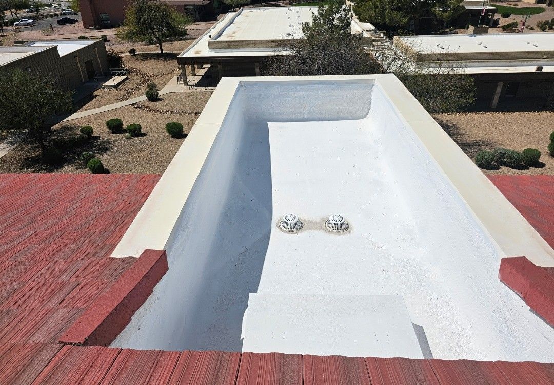 A rectangular white-painted well on a red roof with building backgrounds.